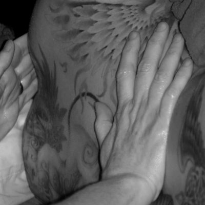 Black and white image of a person with tattoos receiving a back massage close up